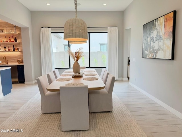 dining area featuring light wood-style floors, recessed lighting, baseboards, and indoor wet bar