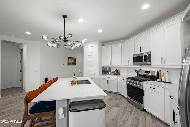 435 E Shellie Ct, Casa Grande, AZ 85122 - kitchen with appliances with stainless steel finishes, a sink, a kitchen bar, light wood-style flooring, and decorative backsplash