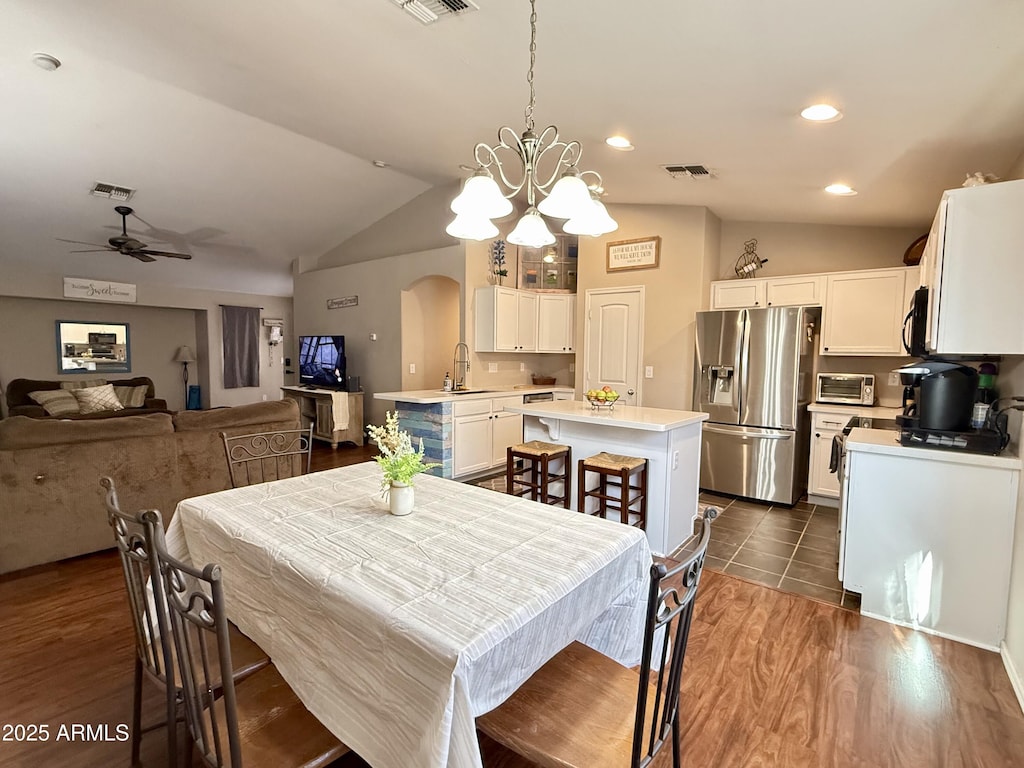 45499 W Sky Ln, Maricopa, AZ 85139 - dining space with arched walkways, vaulted ceiling, ceiling fan, a chandelier, and dark wood-style flooring