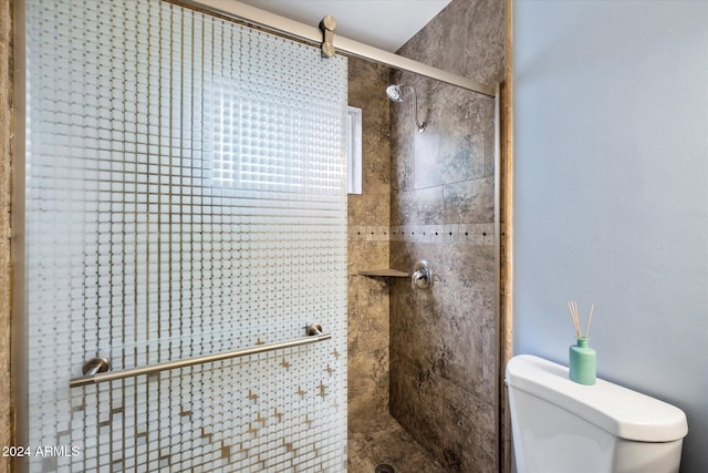 bathroom with a shower with shower door and toilet