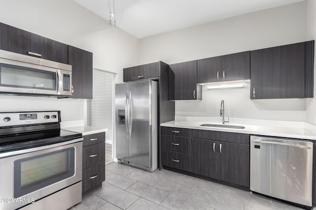 kitchen featuring sink, light tile patterned flooring, a high ceiling, and appliances with stainless steel finishes