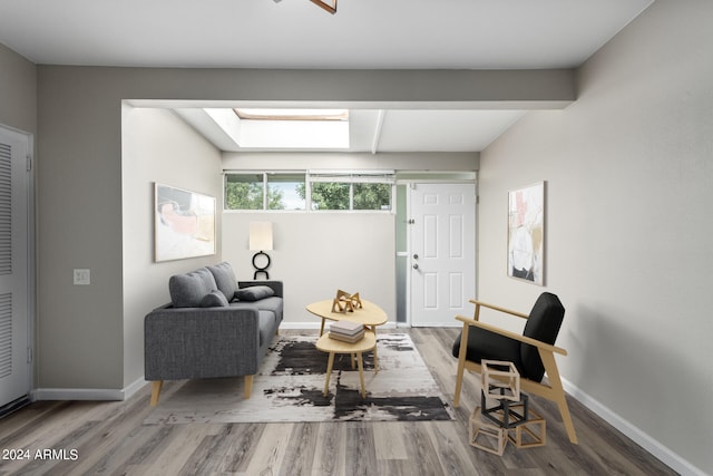 living area with hardwood / wood-style flooring and a skylight