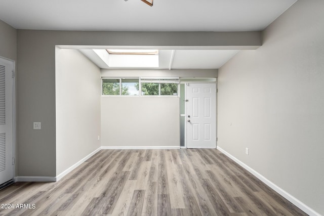 spare room with light hardwood / wood-style flooring and a skylight