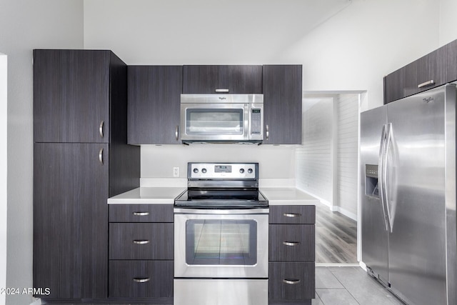 kitchen featuring light tile patterned flooring, appliances with stainless steel finishes, and dark brown cabinets