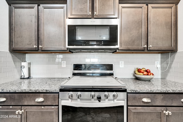 kitchen featuring decorative backsplash, dark brown cabinets, stainless steel appliances, and light stone counters