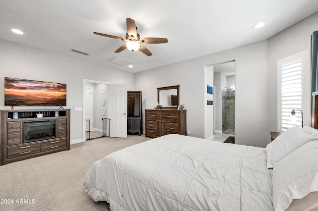 bedroom with ceiling fan, light colored carpet, and ensuite bath