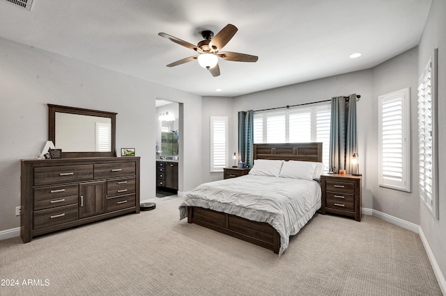 bedroom featuring light carpet, ceiling fan, and ensuite bathroom