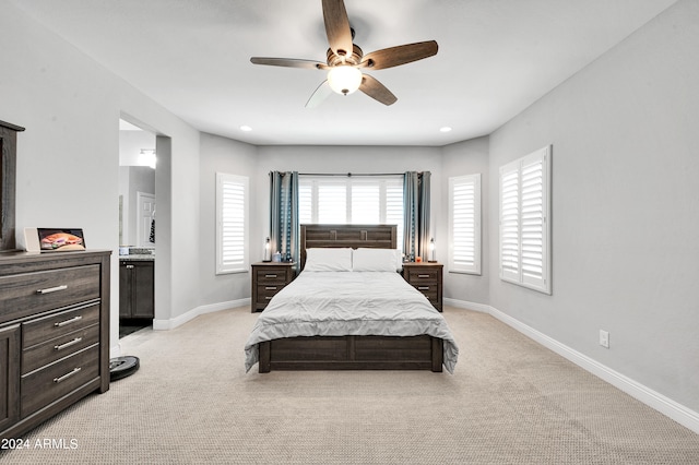 bedroom with light carpet, ensuite bath, and ceiling fan