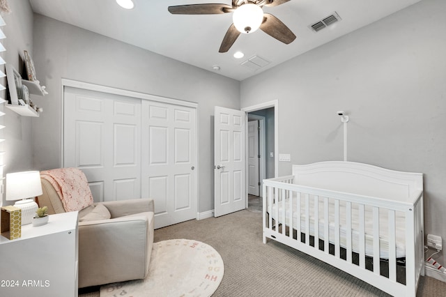 bedroom featuring light carpet, a closet, ceiling fan, and a nursery area