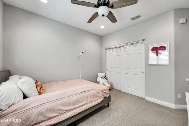 bedroom with ceiling fan, light colored carpet, and a closet