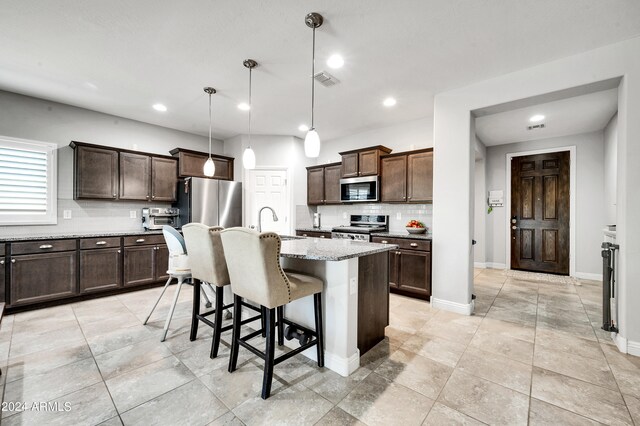 kitchen with appliances with stainless steel finishes, hanging light fixtures, a center island with sink, and dark brown cabinets