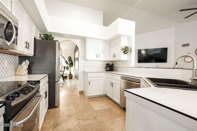 kitchen with sink, ceiling fan, white cabinetry, stainless steel appliances, and tasteful backsplash