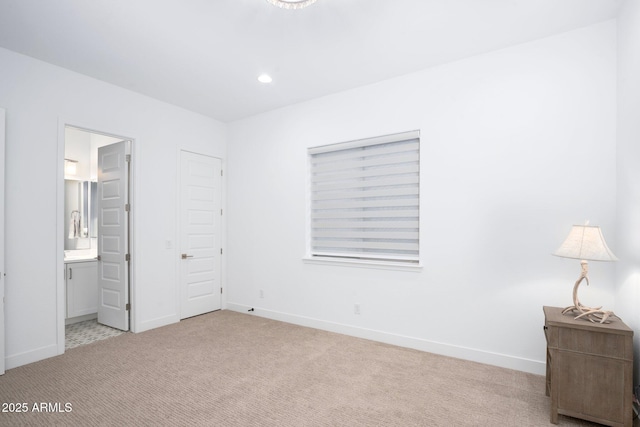 bedroom featuring ensuite bath, a closet, and light carpet