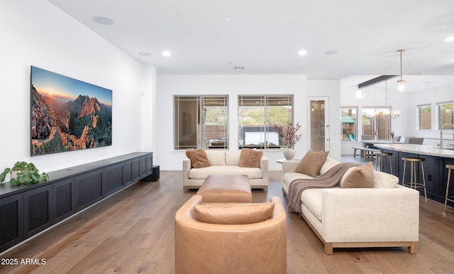 living room with vaulted ceiling, a notable chandelier, and light hardwood / wood-style floors