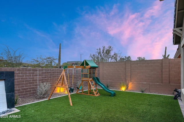 playground at dusk featuring a lawn