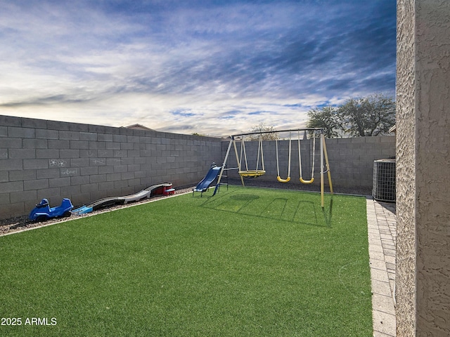 view of yard with central AC, a playground, and a fenced backyard