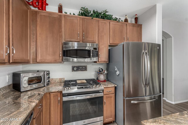 kitchen with decorative backsplash, dark hardwood / wood-style floors, stainless steel appliances, and stone countertops