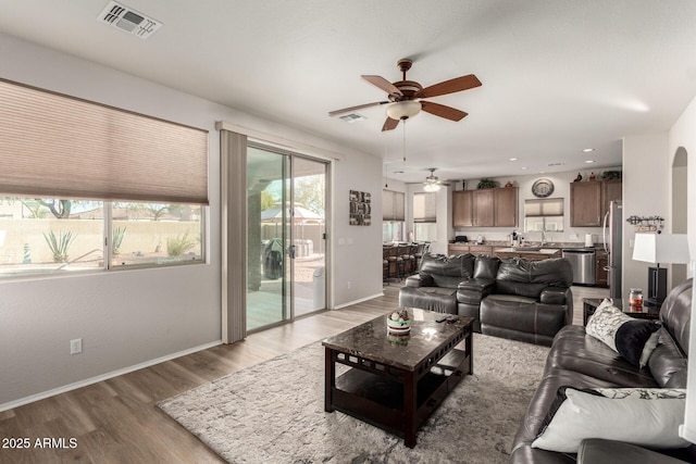 living room with wood-type flooring, ceiling fan, and sink