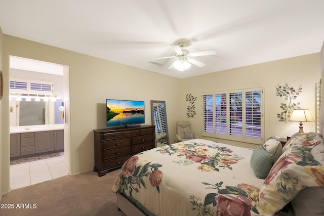 bedroom featuring light carpet, ceiling fan, and ensuite bathroom