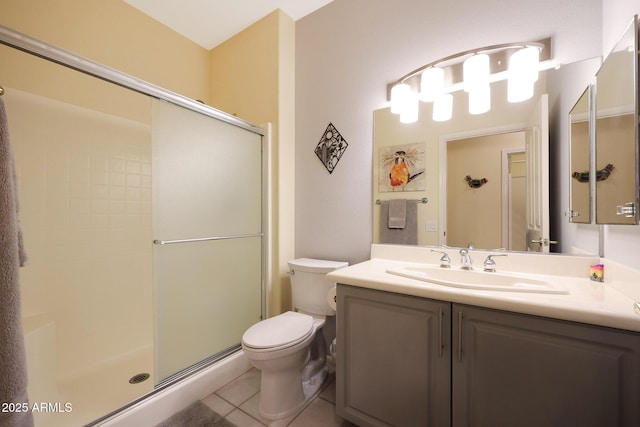 bathroom with a shower with door, vanity, tile patterned floors, and toilet