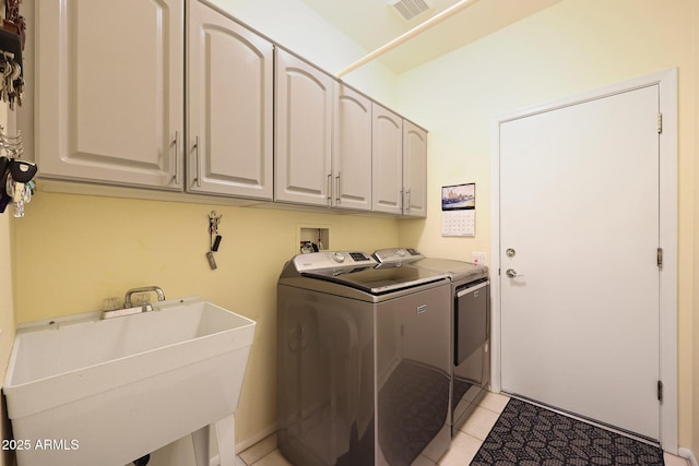 washroom with cabinets, sink, washer and dryer, and light tile patterned flooring