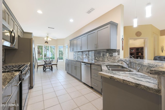 kitchen featuring sink, hanging light fixtures, appliances with stainless steel finishes, gray cabinets, and dark stone counters