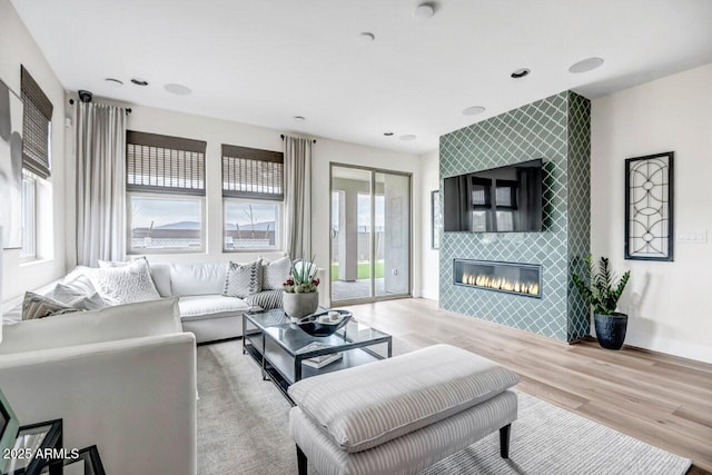 living room with light wood-type flooring and a tile fireplace