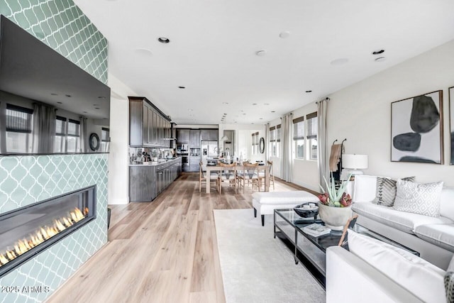 living room with a tile fireplace and light hardwood / wood-style flooring