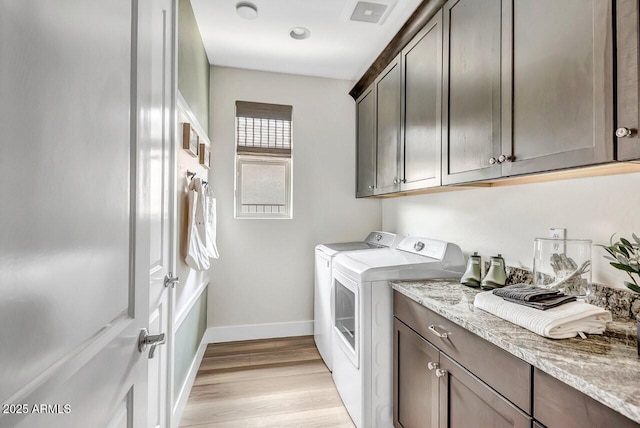 laundry room featuring separate washer and dryer, light hardwood / wood-style floors, and cabinets