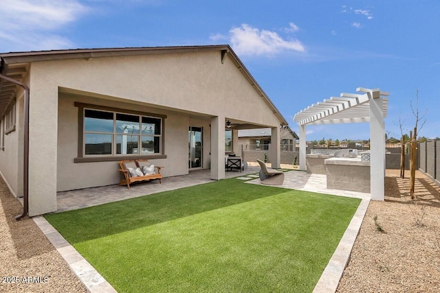 rear view of property with a lawn, exterior kitchen, a pergola, and a patio