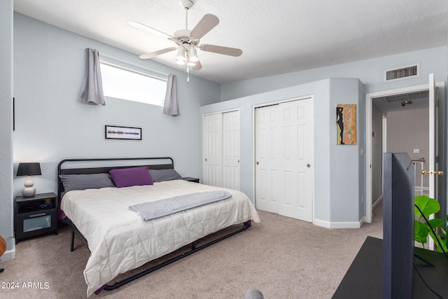 bedroom featuring carpet flooring, ceiling fan, and two closets