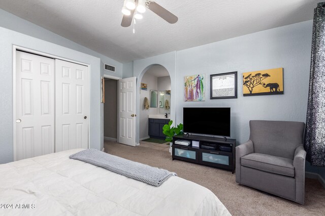 carpeted bedroom featuring lofted ceiling, ensuite bathroom, ceiling fan, a textured ceiling, and a closet