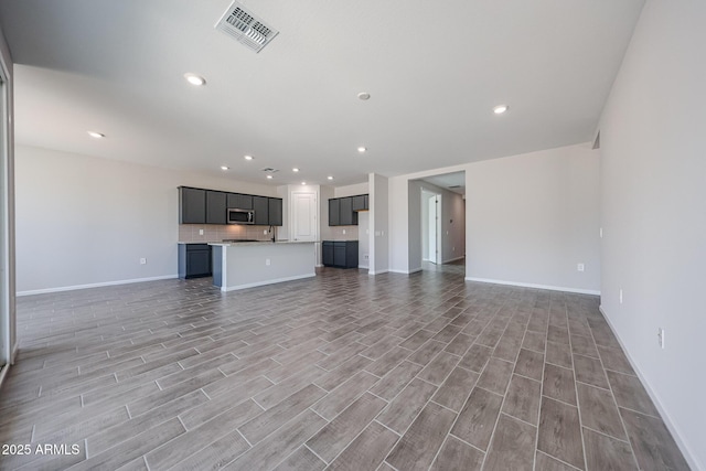 17716 W Fulton St, Goodyear, AZ 85338 - unfurnished living room featuring baseboards, recessed lighting, light wood-style flooring, and visible vents