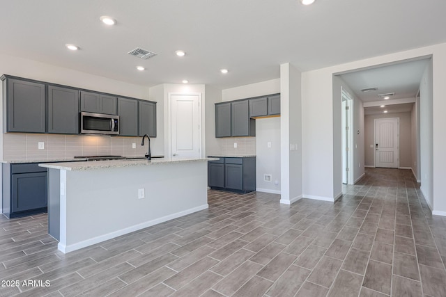 17716 W Fulton St, Goodyear, AZ 85338 - kitchen featuring tasteful backsplash, a sink, stainless steel microwave, light wood-type flooring, and visible vents