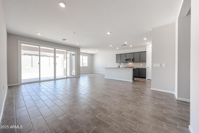 17716 W Fulton St, Goodyear, AZ 85338 - unfurnished living room with a sink, baseboards, recessed lighting, and visible vents