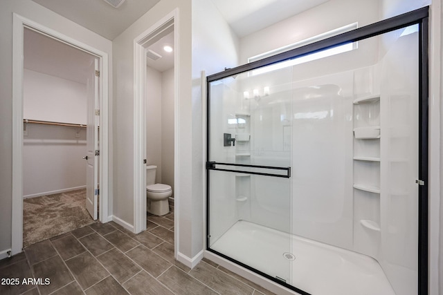 17716 W Fulton St, Goodyear, AZ 85338 - full bath with visible vents, toilet, baseboards, a walk in closet, and a stall shower