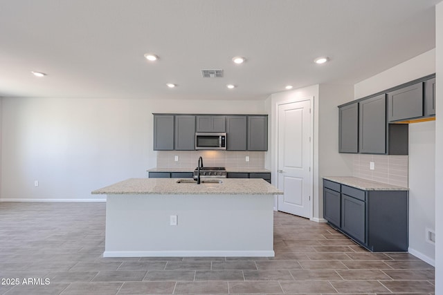 17716 W Fulton St, Goodyear, AZ 85338 - kitchen featuring decorative backsplash, stainless steel microwave, light stone countertops, and visible vents