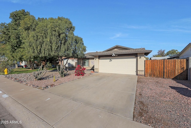 ranch-style house featuring a garage, fence, concrete driveway, and stucco siding