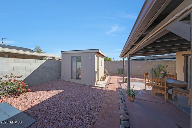 view of patio / terrace featuring outdoor dining space, a fenced backyard, and an outbuilding