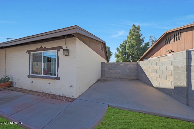 view of property exterior with a patio area and fence