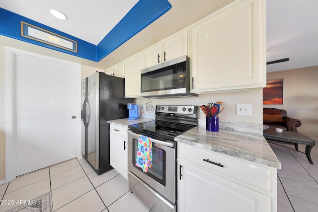 kitchen featuring light tile patterned floors, stainless steel appliances, light stone counters, and white cabinets