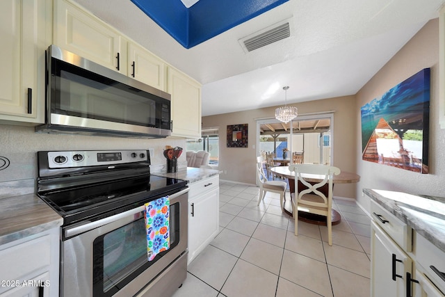 kitchen featuring decorative light fixtures, light tile patterned floors, visible vents, appliances with stainless steel finishes, and baseboards