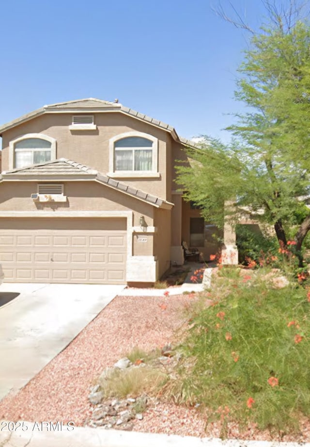 view of front of home with stucco siding, a garage, driveway, and a tile roof