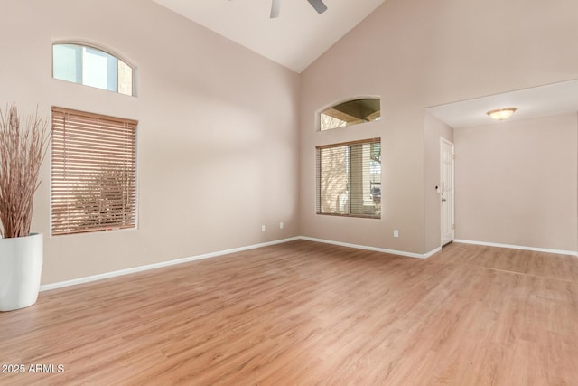 spare room with ceiling fan, baseboards, high vaulted ceiling, and light wood-style flooring