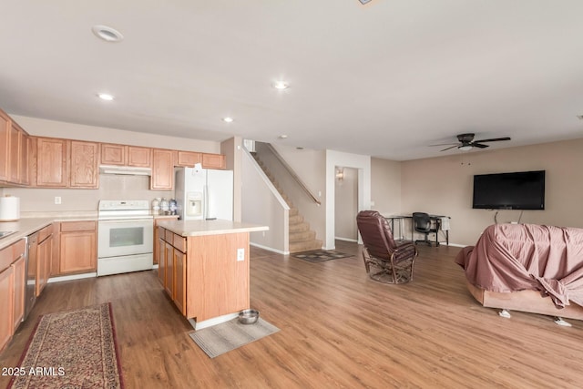 kitchen with white appliances, a kitchen island, light countertops, under cabinet range hood, and open floor plan