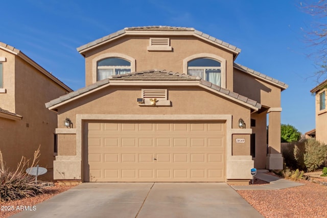 mediterranean / spanish house with stucco siding, an attached garage, driveway, and a tile roof