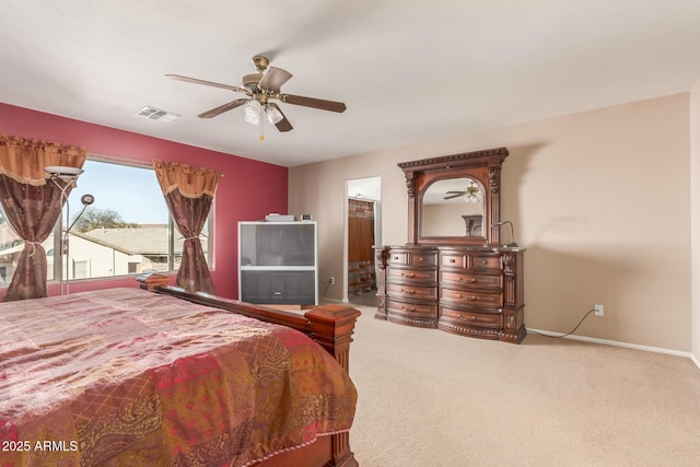 carpeted bedroom with visible vents, baseboards, ensuite bath, and ceiling fan