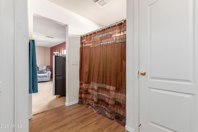 corridor with visible vents, baseboards, and wood finished floors