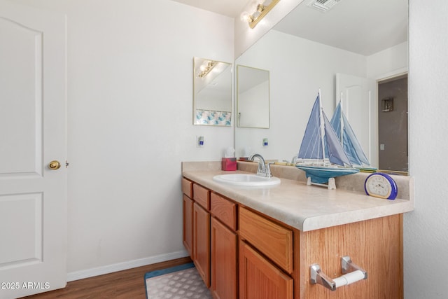 bathroom featuring visible vents, vanity, baseboards, and wood finished floors