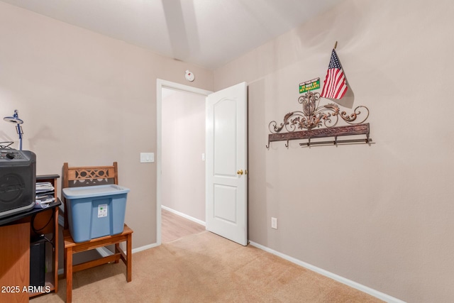 office area featuring baseboards and light carpet